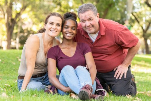 Mature caucasian couple posing with their black adopted daughter