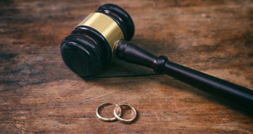 Wedding rings and judge gavel on wooden background, copy space